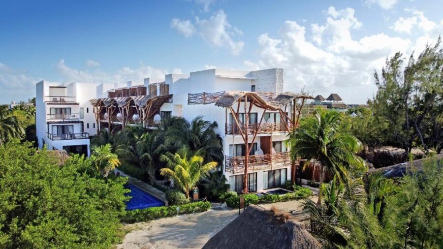 Lush palm trees and vibrant vegetation surround Mystique Holbox by Royalton, creating a tropical resort atmosphere.
