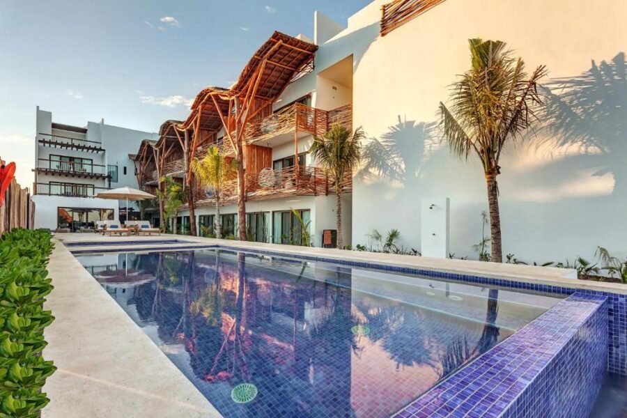 Lush palm trees and vibrant vegetation surround Mystique Holbox by Royalton, creating a tropical resort atmosphere.
