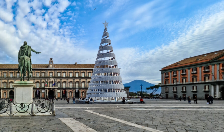 Piazza Del Plebiscito in Naples adorned with a Christmas tree, winter decorations, and a backdrop of Mount Vesuvius