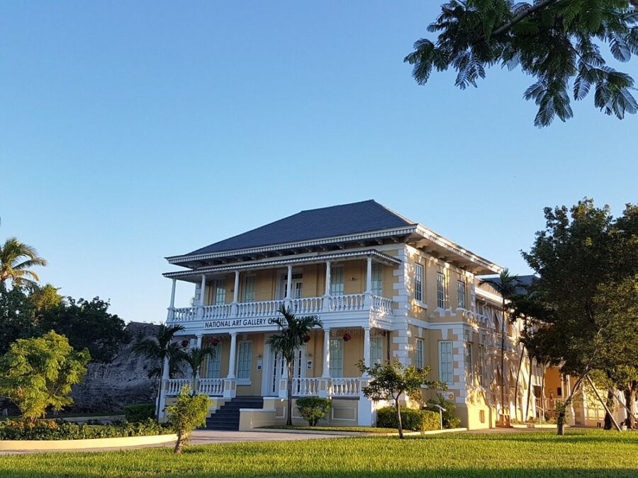 The National Art Gallery of The Bahamas features a large white house with a wide porch and lush trees nearby.