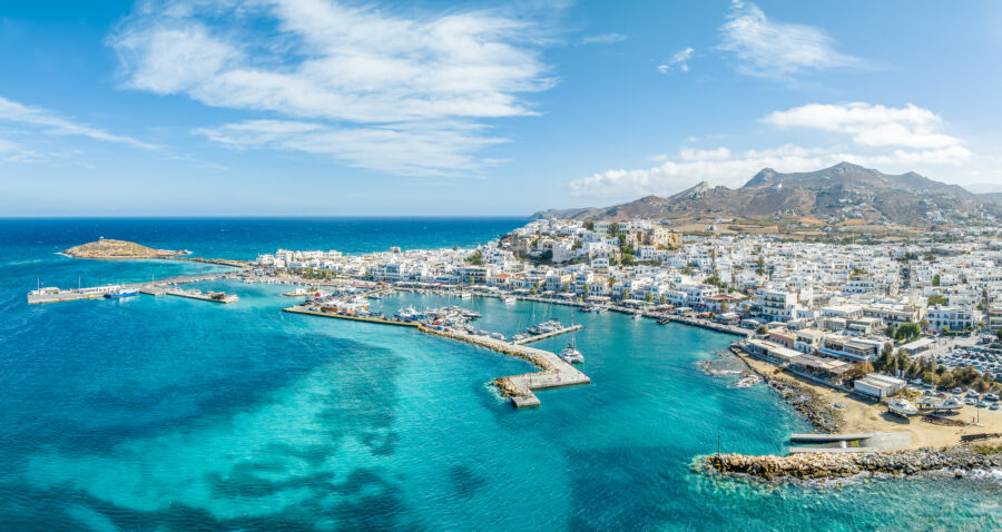 Aerial view of the port of Kos, Greece, showcasing boats and the coastline against a backdrop of blue waters.
