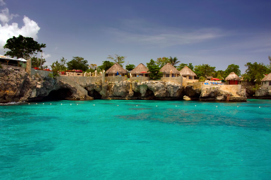 Negril beach in Jamaica, showcasing golden sand, gentle waves, and palm trees swaying in the warm tropical breeze