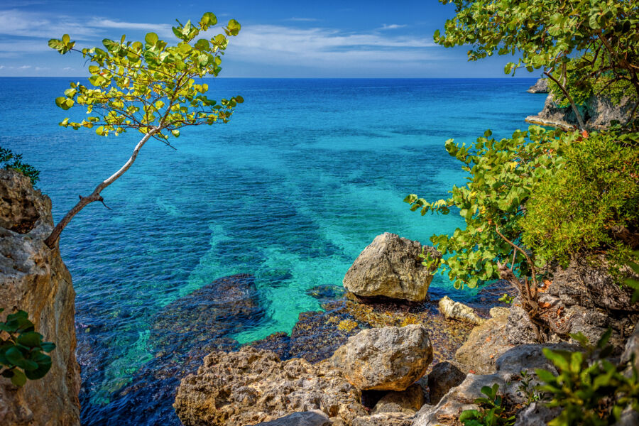 Clear turquoise water lapping against rocky cliffs in Negril, Jamaica, showcasing a stunning Caribbean paradise