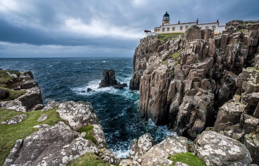 Neist Point Lighthouse perched on a rocky cliff, overlooking the sea on the Isle of Skye.

