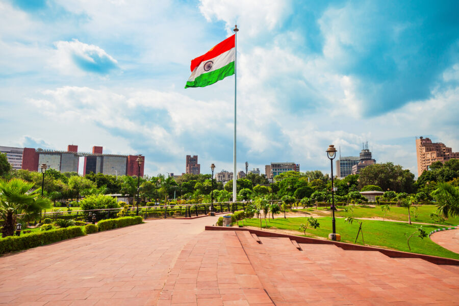 The National Flag of India displayed prominently with a panoramic view of New Delhi's skyline in the background