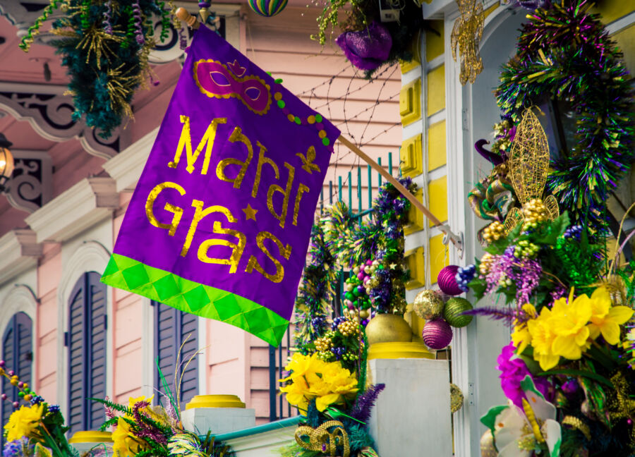 Colorful Mardi Gras decorations adorn a street in New Orleans, Louisiana, featuring beads, masks, and festive banners