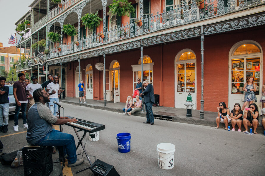 New Orleans street scene with keyboard musician, lively crowd, historic architecture, and community spirit.