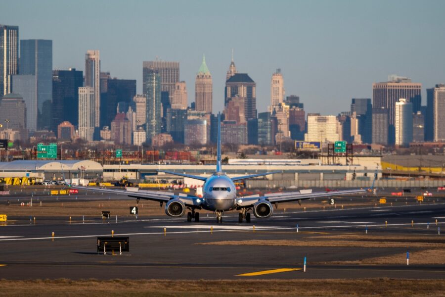Commercial airplane is on the taxiway at Newark Airport, with the New York City skyline in the background.