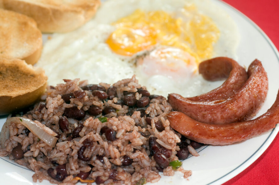 Traditional Nicaraguan breakfast featuring gallo pinto, scrambled eggs, and sausage on a colorful plate 