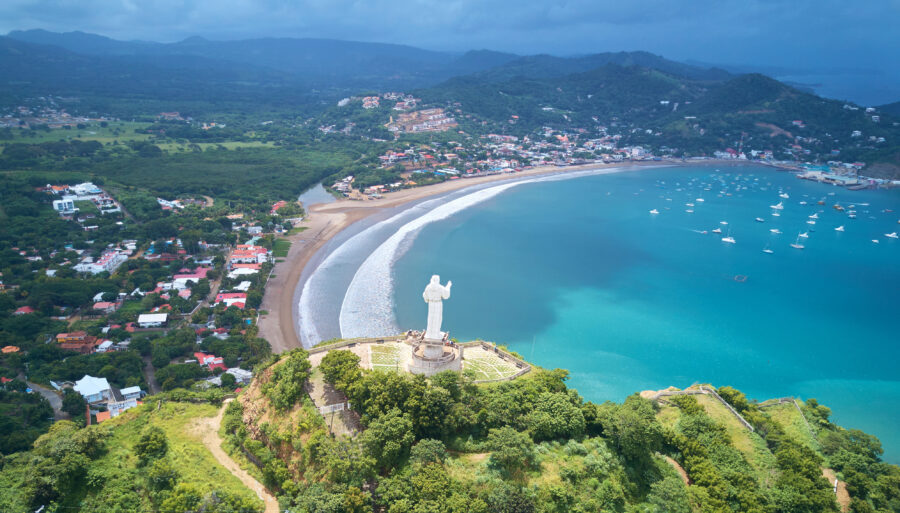Scenic panorama of San Juan Del Sur, Nicaragua, featuring the beach, lush hills, and colorful buildings along the coastline