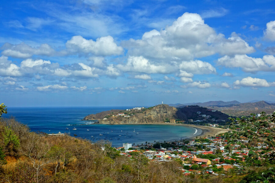 Scenic panorama of San Juan Del Sur, Nicaragua, featuring the beach, lush hills, and colorful buildings along the coastline