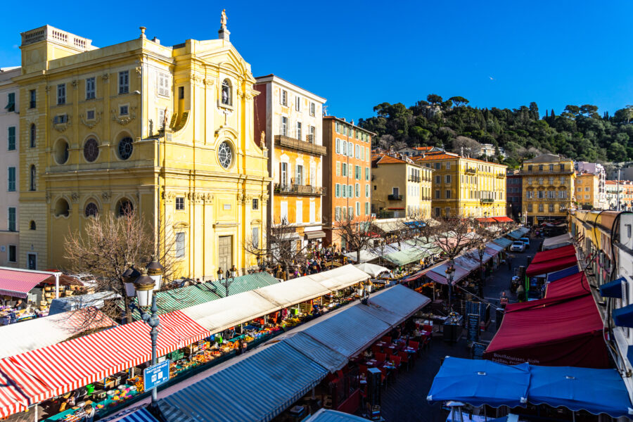 Vibrant view of Cours Saleya, Nice's famous flea market, bustling with tourists and colorful stalls.