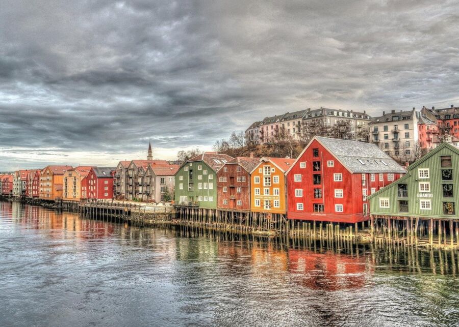 Colorful houses line the Nidelva River in Trondheim, reflecting the vibrant cityscape against the water.