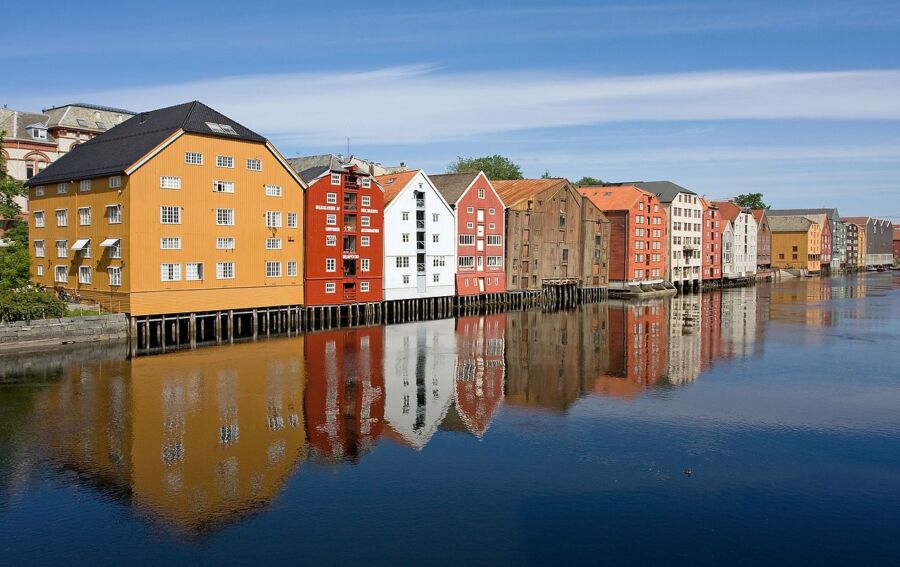 Colorful buildings reflect in the Nidelva River, showcasing the charm of Trondheim, Norway.