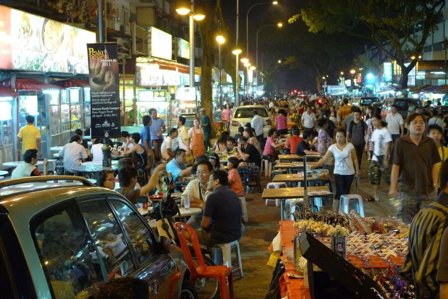 Vibrant night market bustling with food stalls, neon lights, and lively crowds.