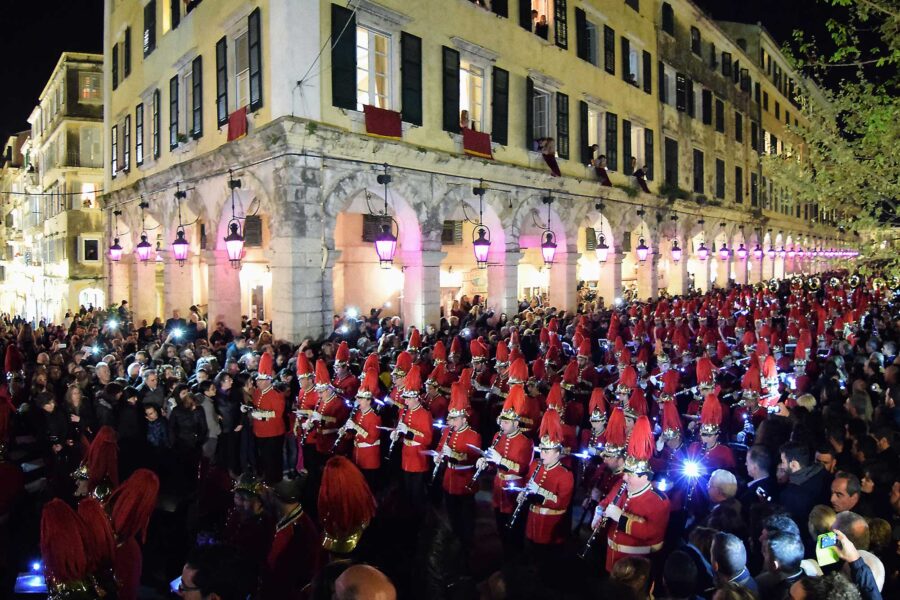 Vibrant nighttime parade with musicians in red uniforms at historic Corfu Easter celebration.