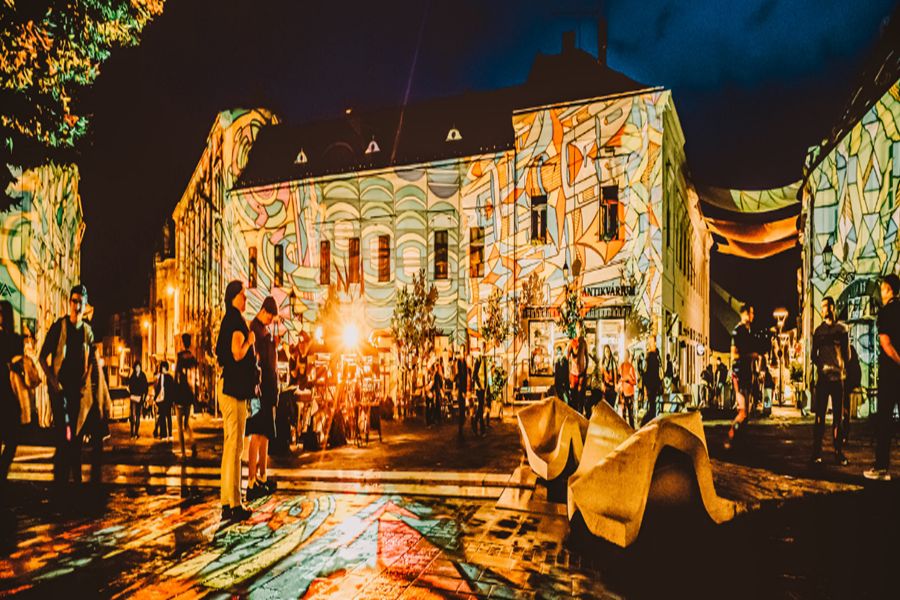 Night building projection mapping in urban square light festival with colorful reflections.