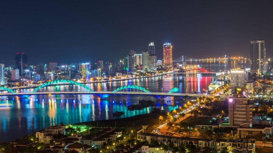 Night city skyline with illuminated bridges reflecting on river in Hai Chau District at dusk.