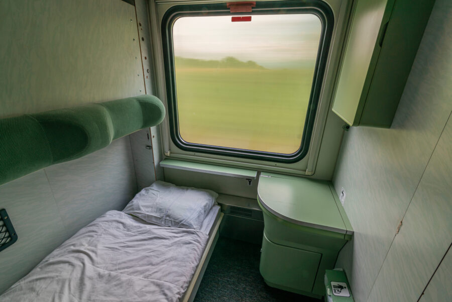 Interior of a single compartment on a night train from Presov to Prague, showcasing a neatly made bed for sleeping.