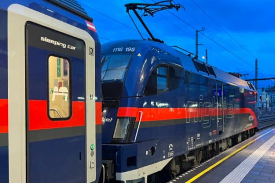 ÖBB Nightjet overnight sleeping car and locomotive on station platform at twilight.