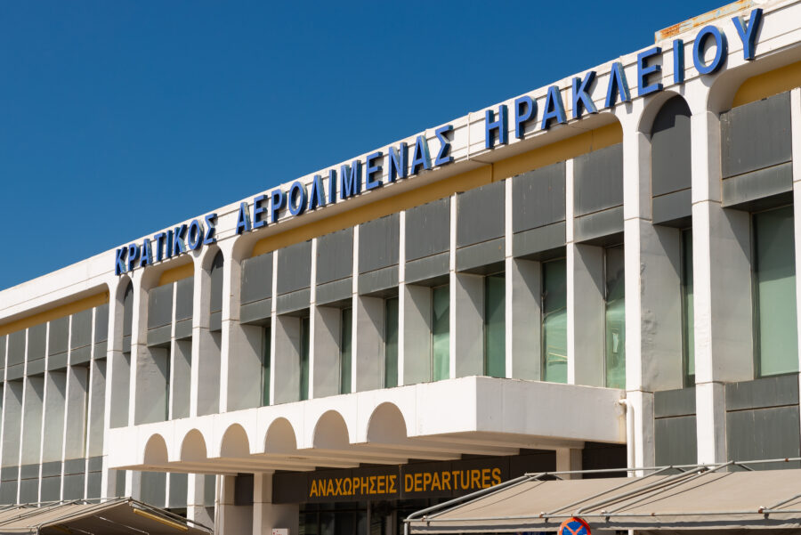 Exterior view of Nikos Kazantzakis Airport, featuring modern architecture and a clear blue sky in the background.
