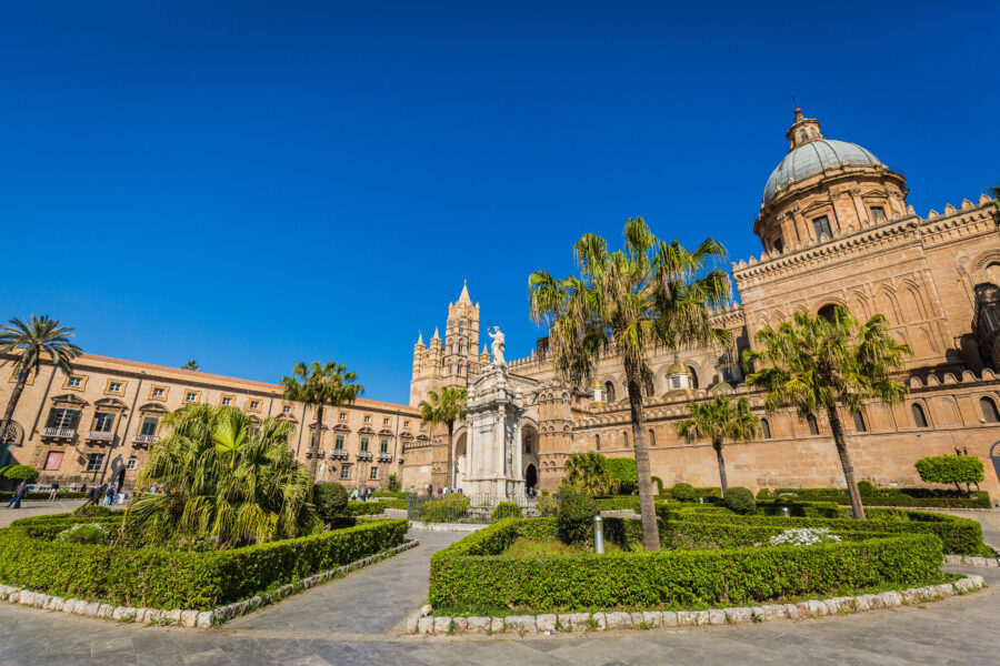 Norman Palace in Palermo, Italy, showcasing its historic architecture and lush gardens under a clear blue sky