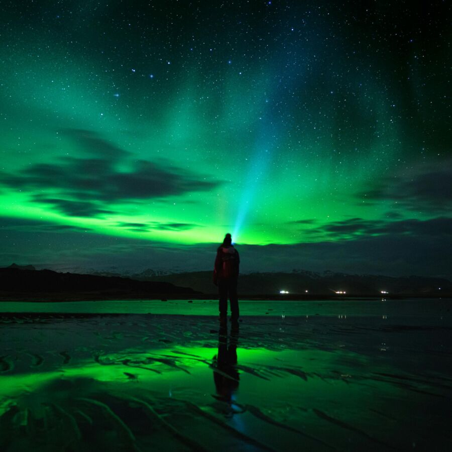 Aurora borealis illuminates sky over reflective water 