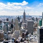New York City skyline featuring Empire State Building under blue sky with clouds.