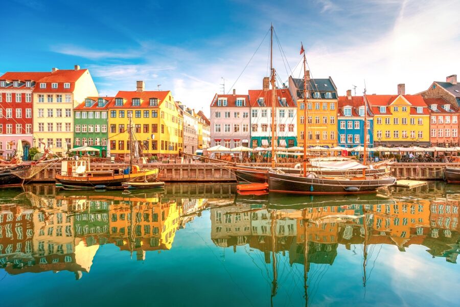 Colorful Nyhavn harbor in Copenhagen with historic ships, vibrant buildings, and serene water reflections.