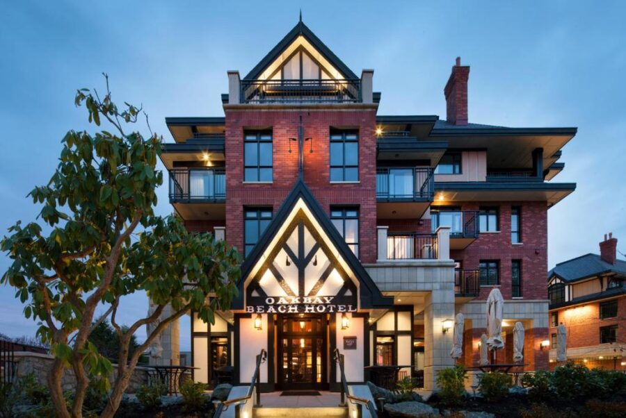 Front entrance of Oak Bay Beach Hotel in Victoria, BC, illuminated at dusk, showcasing elegant architecture and welcoming ambiance.