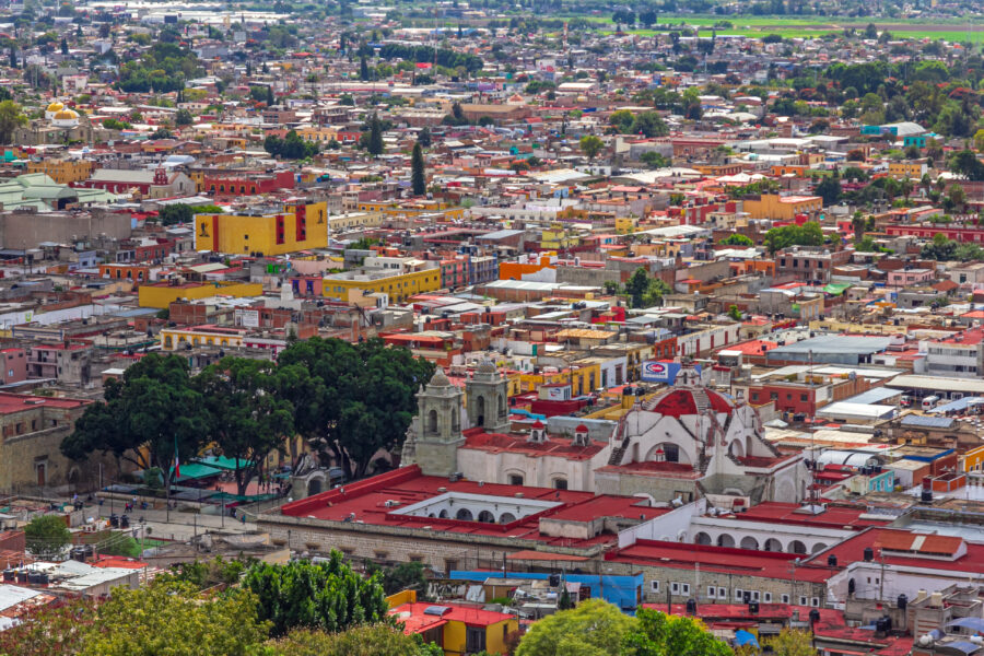 Scenic panorama of Oaxaca, Mexico, featuring colorful architecture, rolling hills, and a bright blue sky.