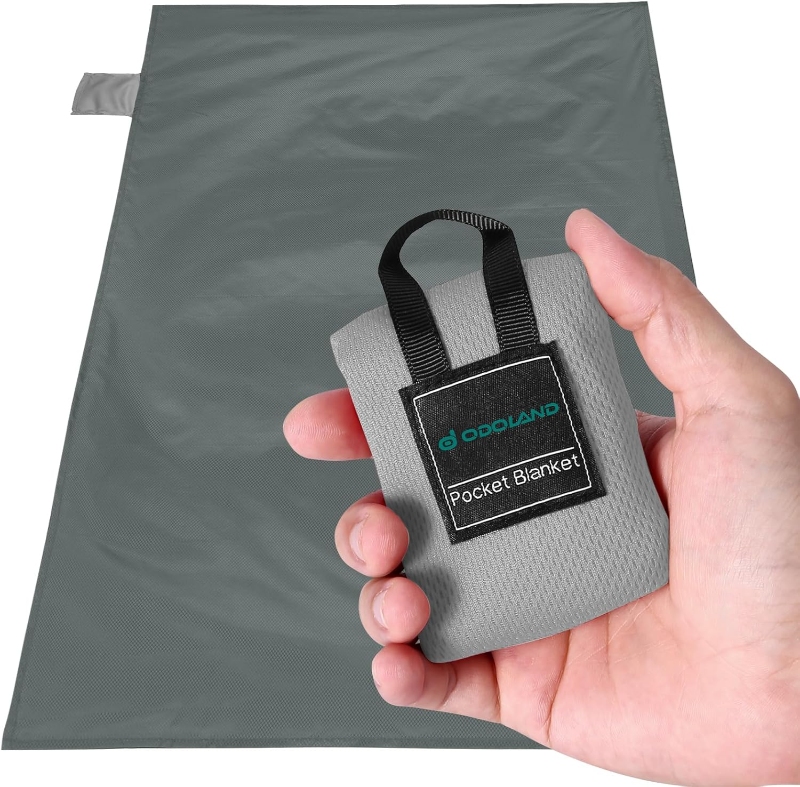 Person displaying a small bag with a tag, identified as the 'Odoland Pocket Beach Blanket'.