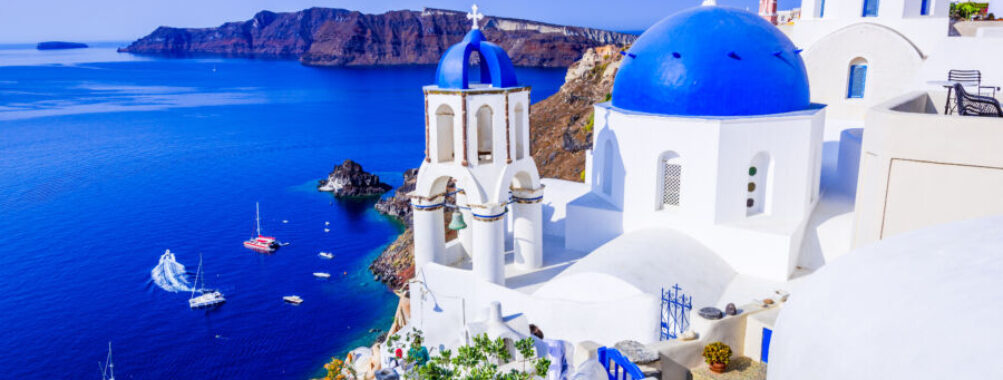 Picturesque view of Oia, Santorini, featuring a blue-domed church overlooking the stunning caldera