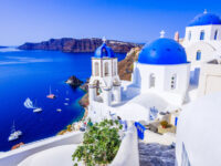 Picturesque view of Oia, Santorini, featuring a blue-domed church overlooking the stunning caldera