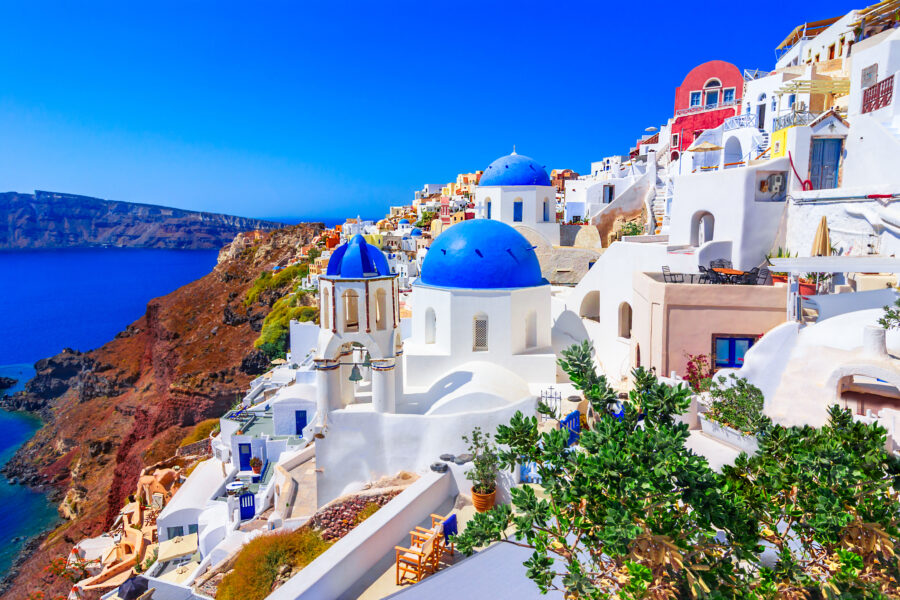 Scenic view of Oia, Santorini, showcasing whitewashed buildings and blue domes against a vibrant sunset sky