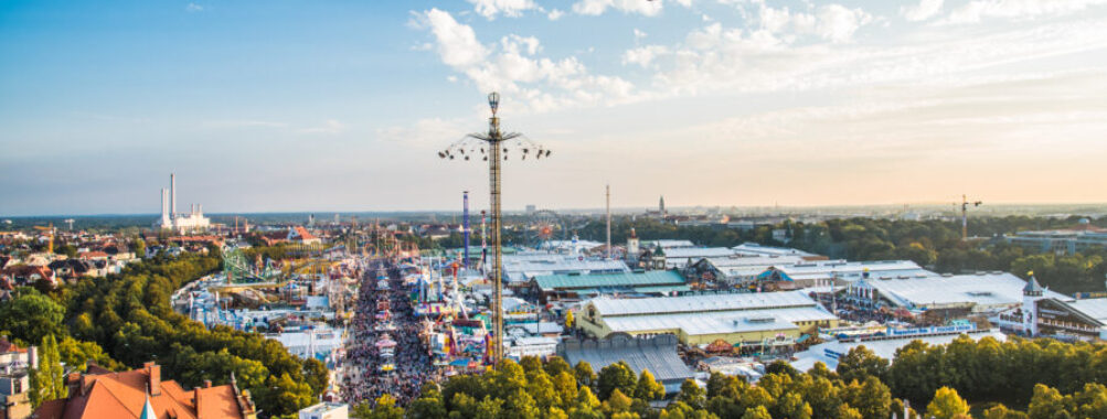 Festive atmosphere inside a Munich beer tent, with a large crowd enjoying Oktoberfest, surrounded by traditional decorations.