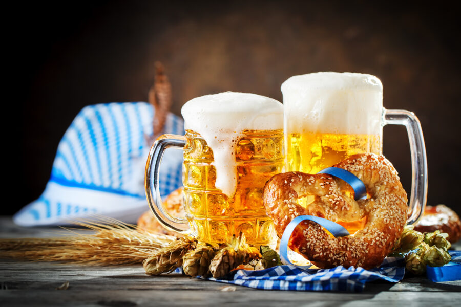 Oktoberfest scene featuring beer mugs and pretzels on a rustic wooden table, highlighting the beer festival atmosphere.