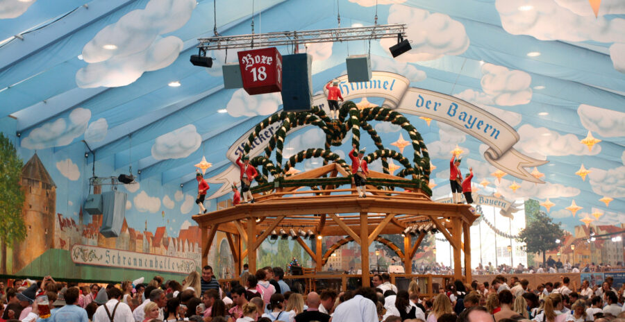 Festive atmosphere inside a Munich beer tent, with a large crowd enjoying Oktoberfest, surrounded by traditional decorations.