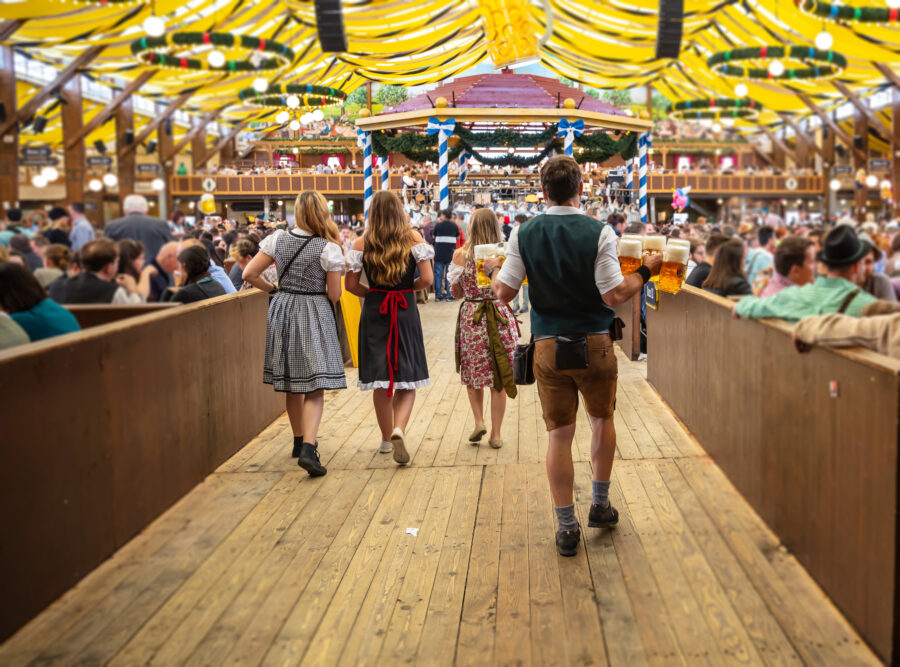Oktoberfest celebration in Munich, Germany, showcasing festive tents, people enjoying beer, and traditional German food.