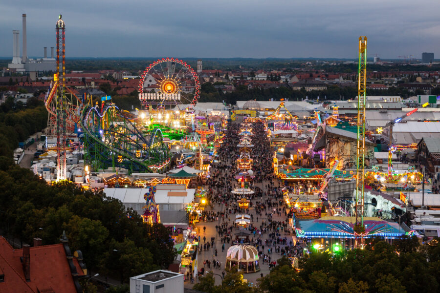 Night view of Oktoberfest in Munich, showcasing illuminated tents and festive crowds enjoying the celebration.
