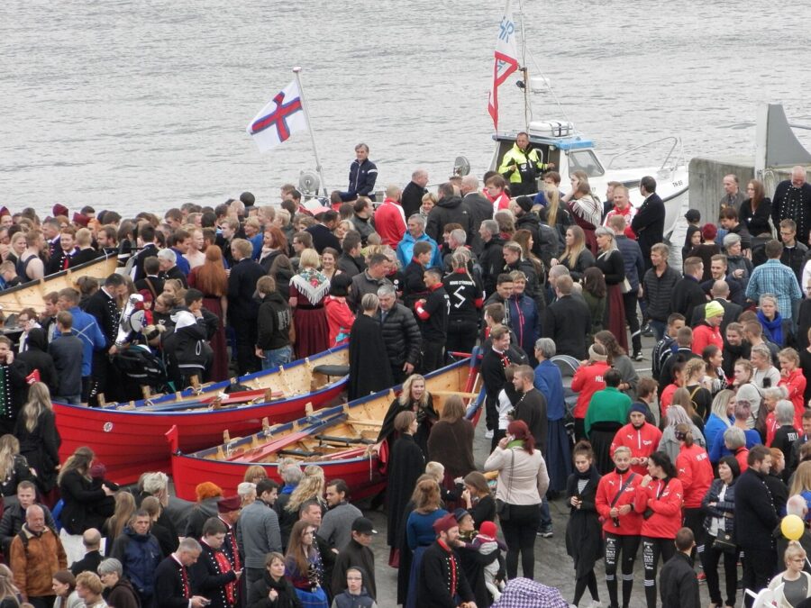 People stand around a boat, celebrating Ólavsøka, the National Day of the Faroe Islands.