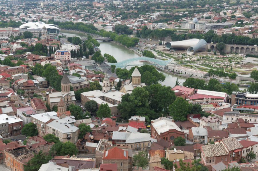 Scenic aerial shot of Old Tbilisi along the Kura River, highlighting the blend of nature and historic buildings.
