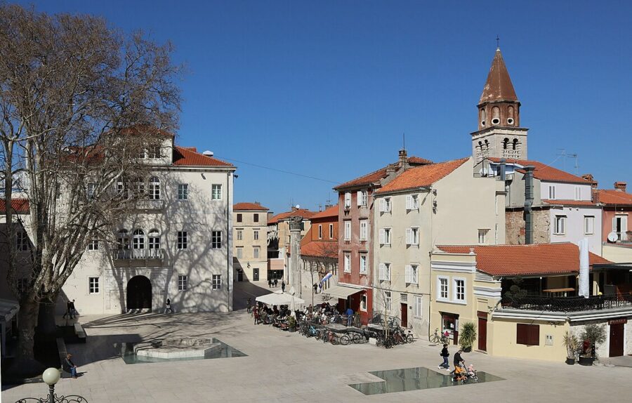 View of a square in Old Town Zadar, Croatia, showcasing a clock tower alongside a beautiful church.
