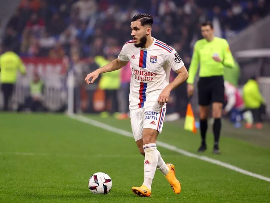 Lyon football player in white jersey focusing on action in vibrant stadium.