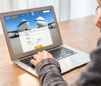 Modern flight booking interface on laptop, businessman browsing for travel, technology in travel booking.