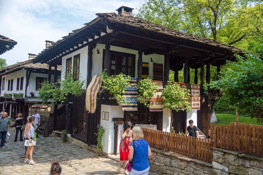 Visitors stroll through a quaint village featuring traditional wooden houses at the Open Air Ethnographic Museum ETAR.

