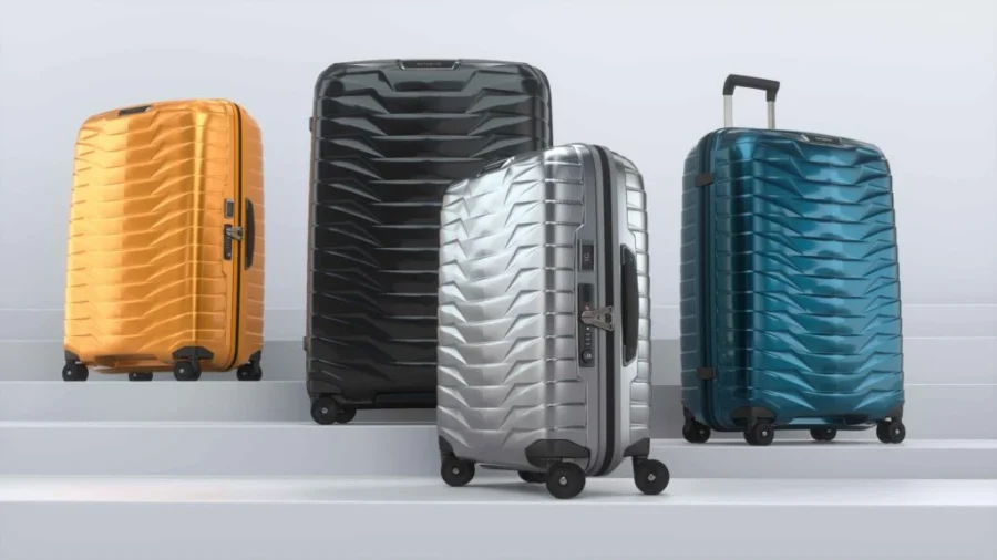 Modern luggage collection in vibrant orange, blue, black, and silver on stairs.