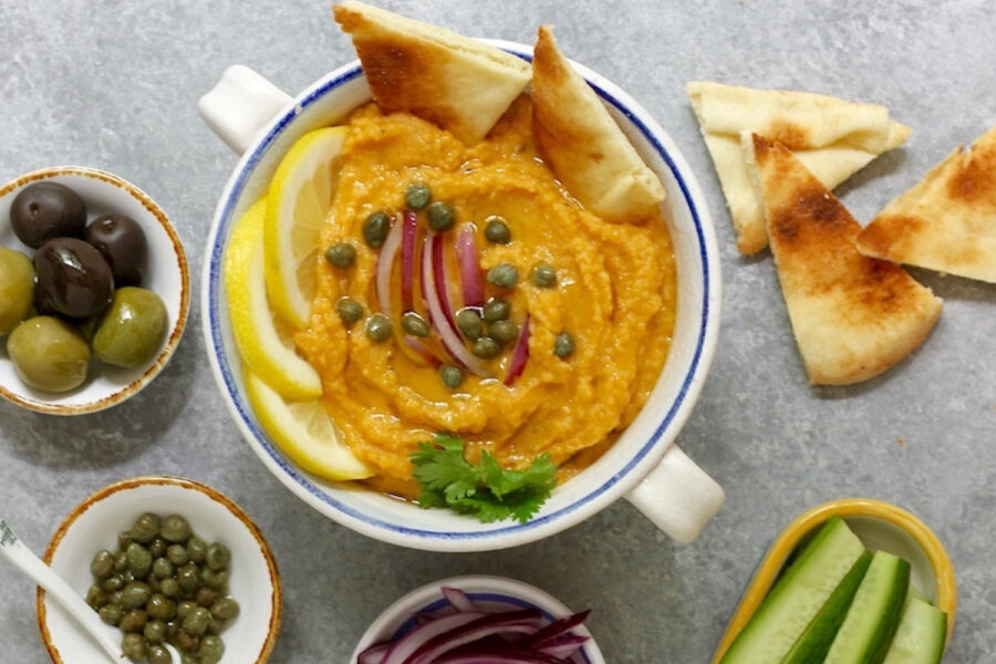 Creamy hummus dip with lemon, red onion, capers, olives, and toasted pita bread.