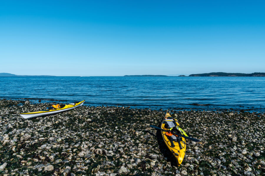 Colorful kayaks lined up on the sandy beach of Orcas Island, surrounded by the scenic beauty of the San Juan Islands.