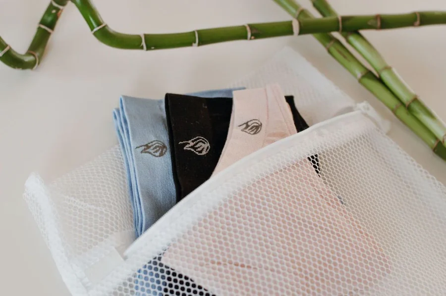 Neatly folded clothing in a transparent mesh bag with bamboo background.